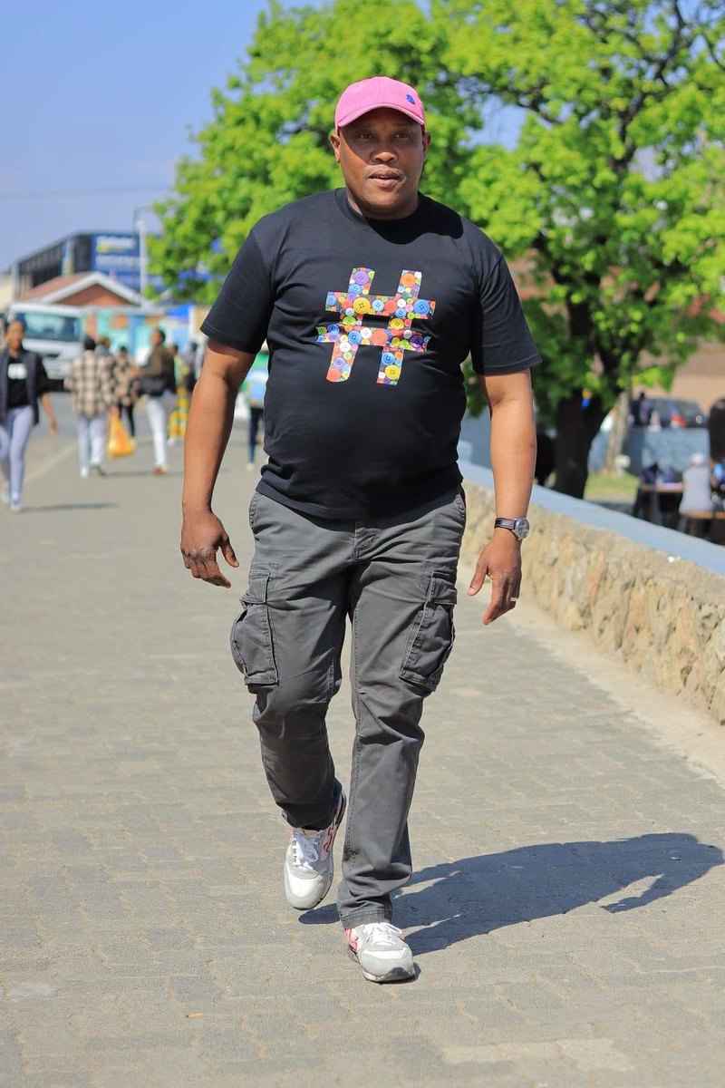 The button hashtag tee worn on a street in Maseru